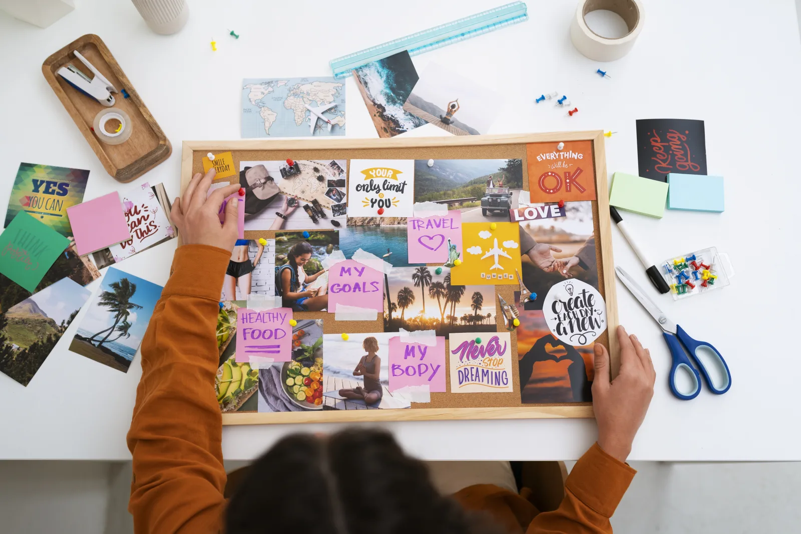 Hands arranging photographs and colour notes on an inspiration board